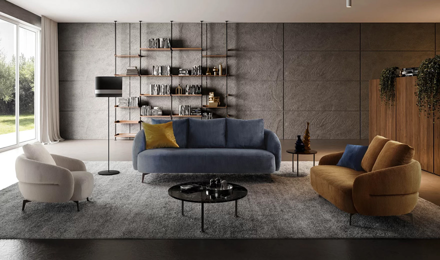 Salon moderne avec un canapé bleu en velours côtelé, une banquette jaune moutarde et un fauteuil crème, disposés sur un tapis gris avec une décoration minimaliste et une bibliothèque murale.