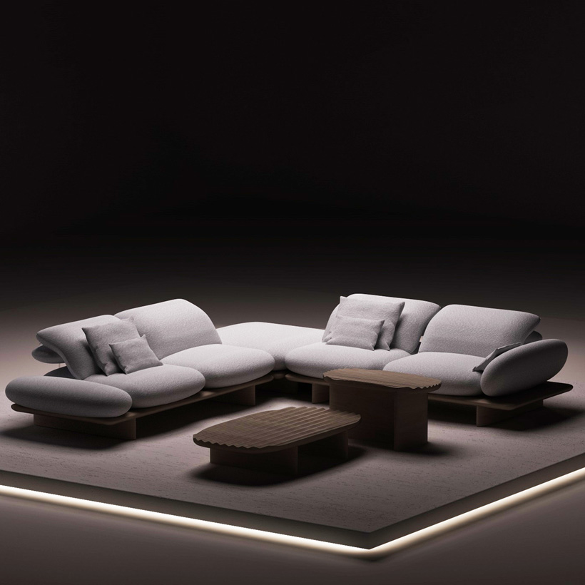 Light gray sectional sofa with organic shapes, paired with wooden coffee tables on an illuminated platform, in a minimalist and contemporary setting.