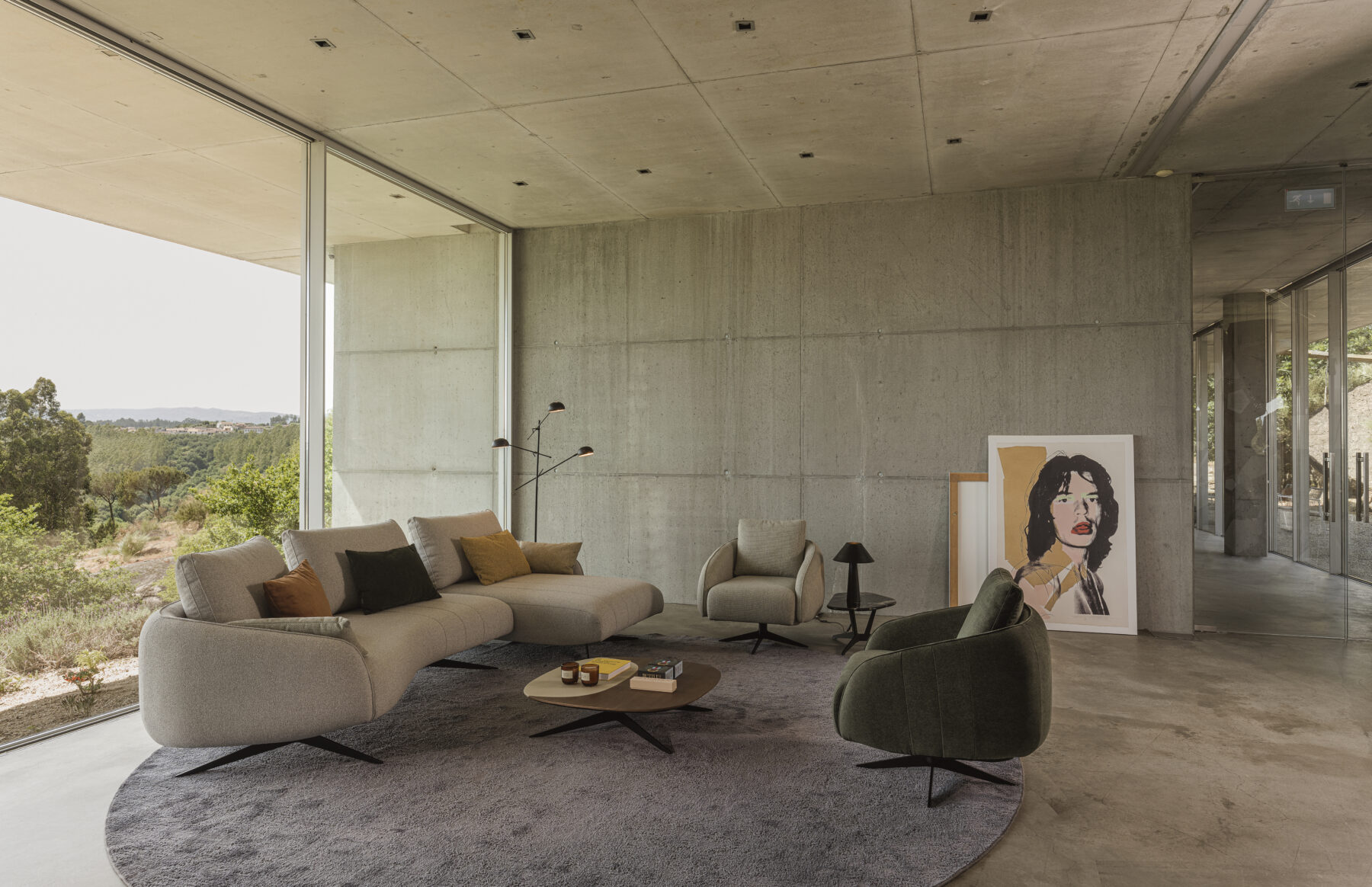 Sculptural sofa with an elongated silhouette, textured beige upholstery, recessed slim legs, and organic lines inspired by pebbles.