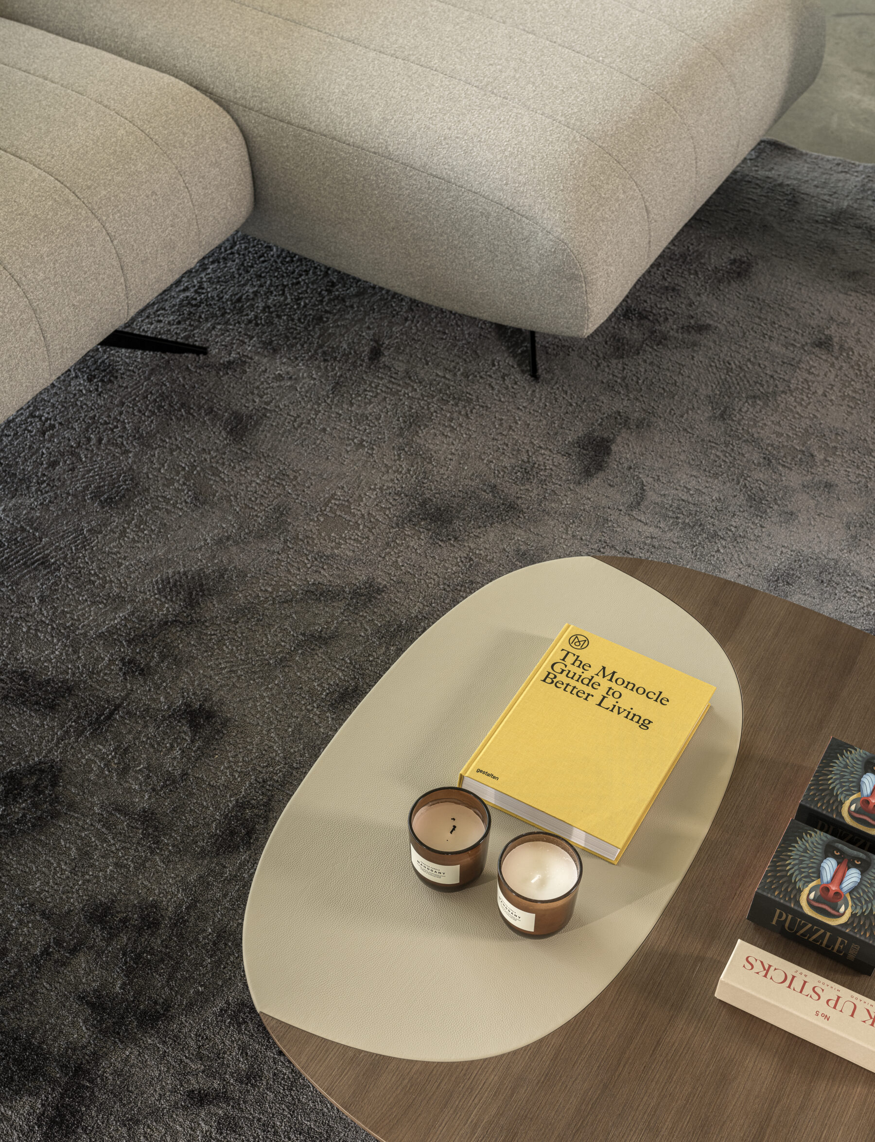 Sculptural sofa with an elongated silhouette, textured beige upholstery, recessed slim legs, and organic lines inspired by pebbles.