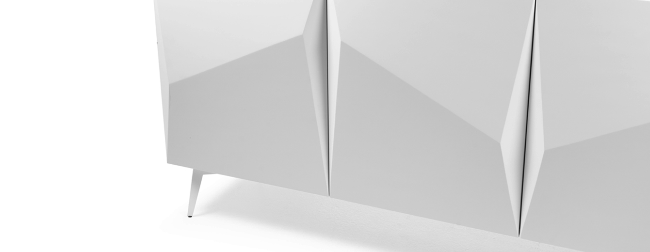Buffet laqué blanc à quatre portes, présentant des façades sculptées en plis géométriques et reposant sur des pieds fins en métal.