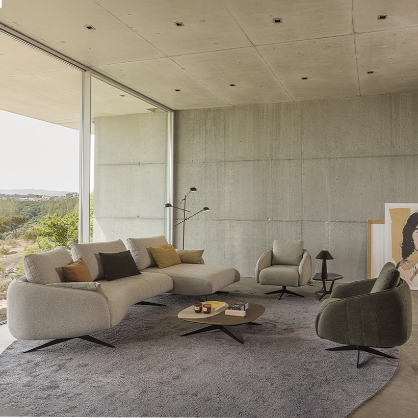 Sculptural sofa with an elongated silhouette, textured beige upholstery, recessed slim legs, and organic lines inspired by pebbles.