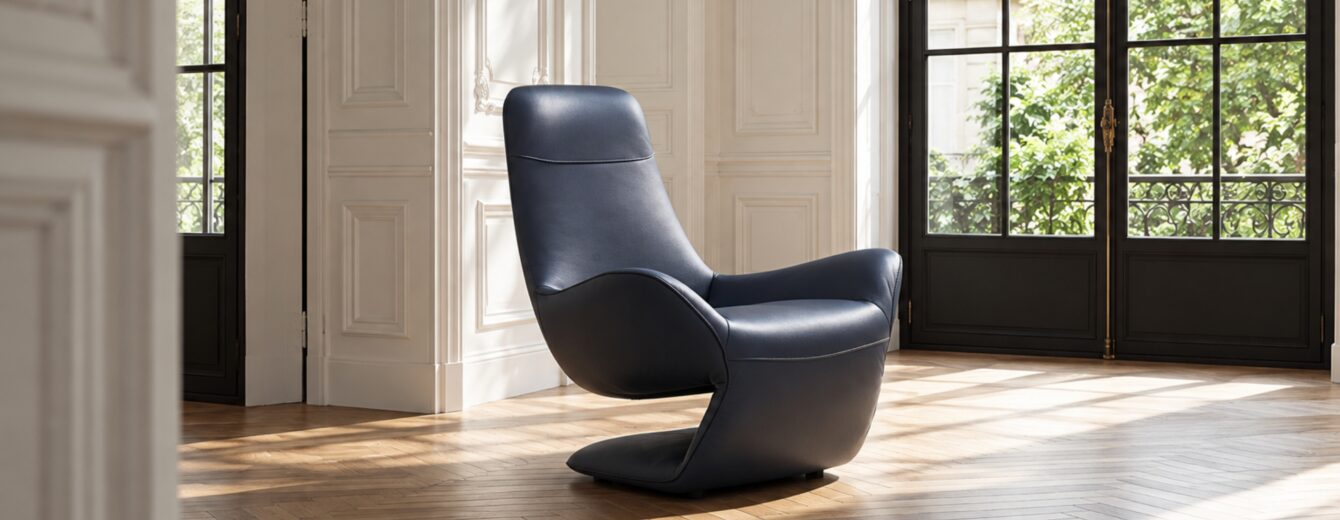 Fauteuil sculptural en cuir bleu profond, avec un dossier haut, des courbes fluides et des accoudoirs enveloppants.
